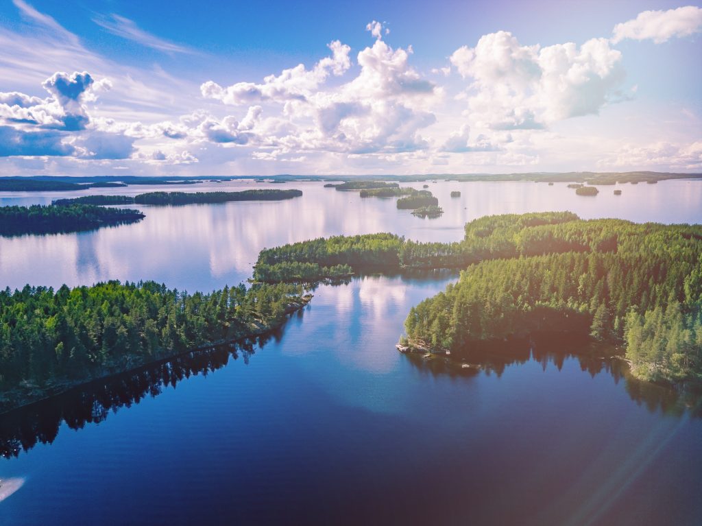 Aerial view of blue lakes and green woods in summer Finland. Beautiful landscape with sunlights